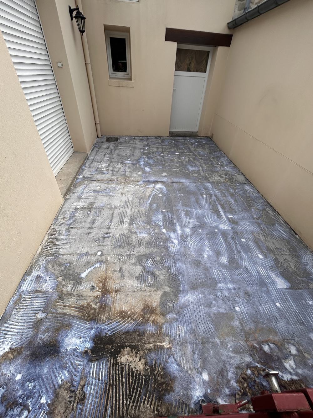 Cour avant travaux : dalle béton avec traces de colle