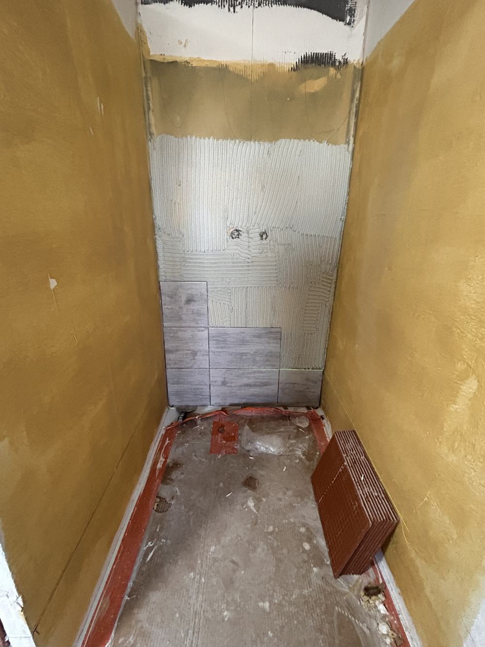 Douche en cours de pose : colle au mur et premiers carreaux