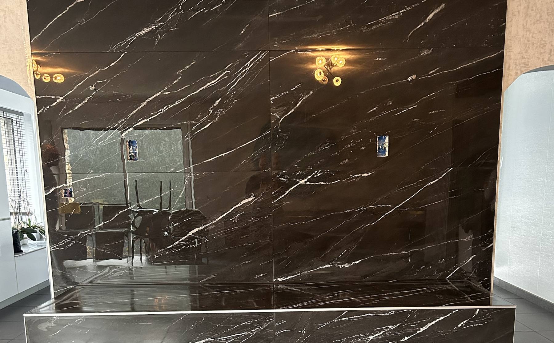 Mur et marche habillés de grandes dalles de marbre noir veiné de blanc