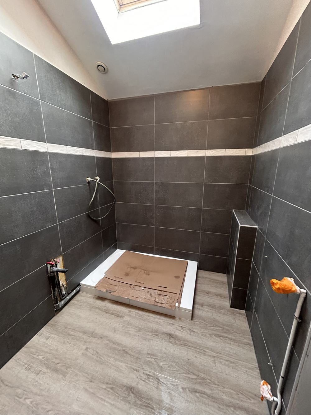 Salle de bain après travaux : murs anthracite avec frise claire et receveur de douche